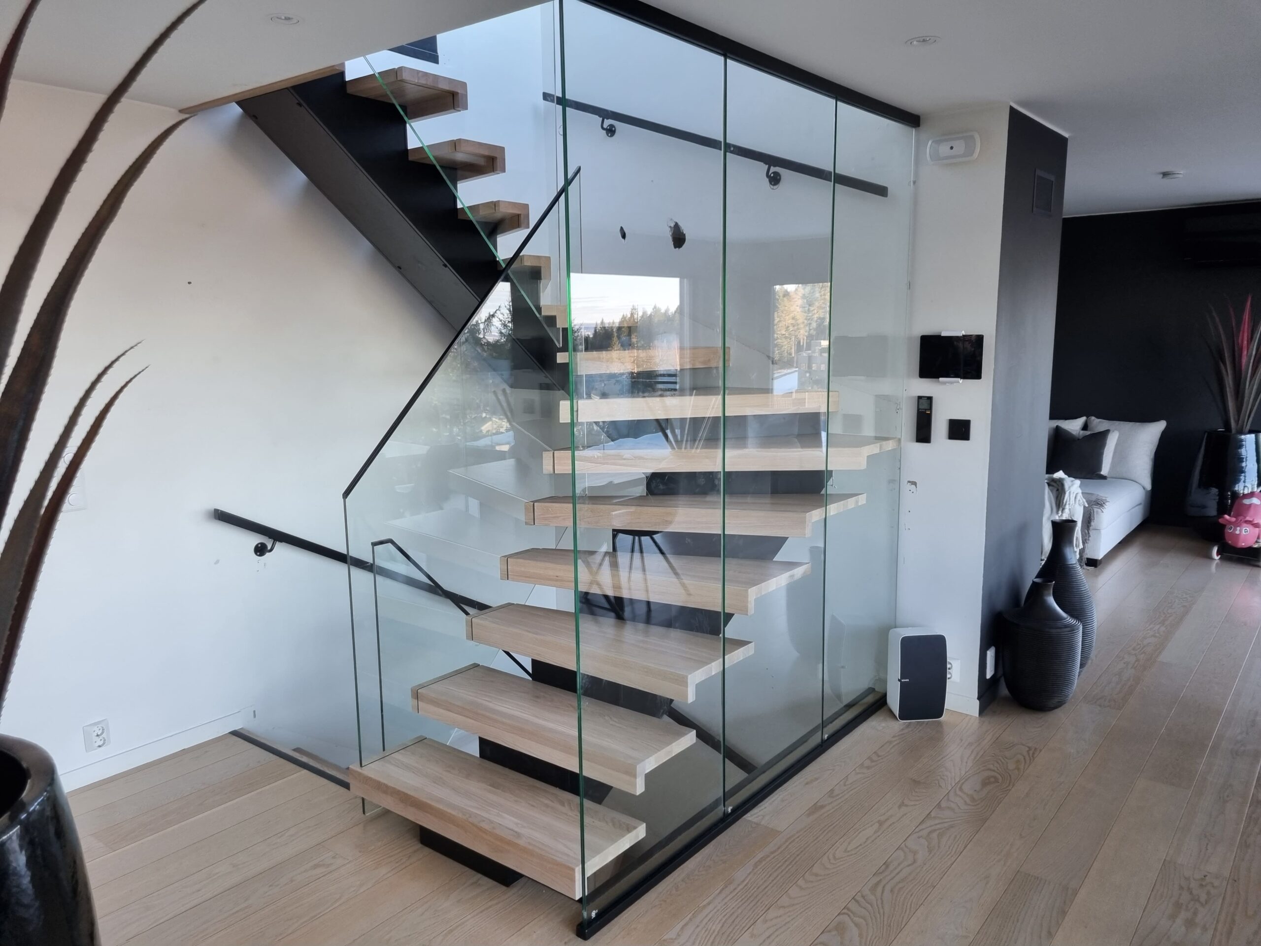 Treppe mit Glasgeländer aus hellem Holz mit Mittelholm