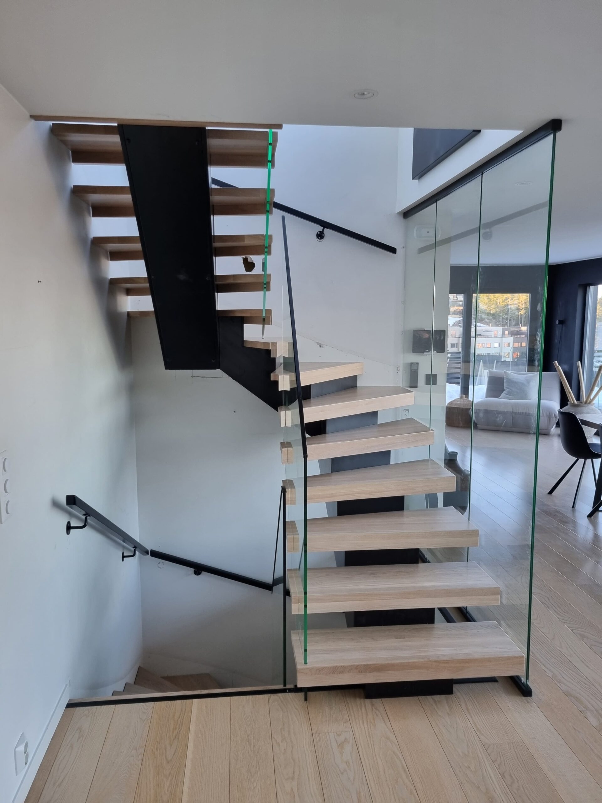 Treppe mit Glasgeländer und Mittelholm über zwei Etagen